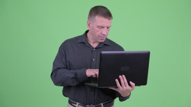 Мачо зрелый бизнесмен думает во время использования ноутбука — стоковое видео