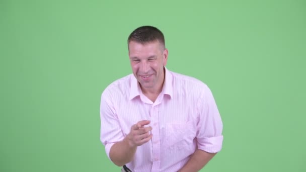 Щасливий зрілий мачо бізнесмен сміється і вказує на камеру — стокове відео