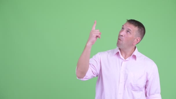 Щасливий зрілий мачо бізнесмен вказує вгору і виглядає здивованим — стокове відео