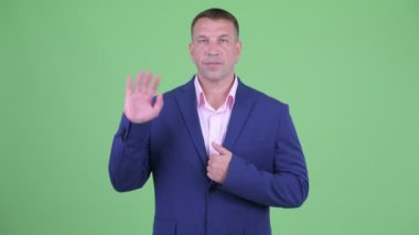 Takım elbiseli olgun maço işadamı el sallıyor