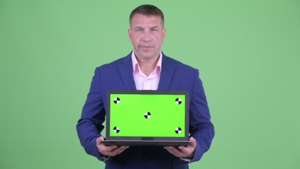Взрослый мачо-бизнесмен в костюме показывает ноутбук — стоковое видео