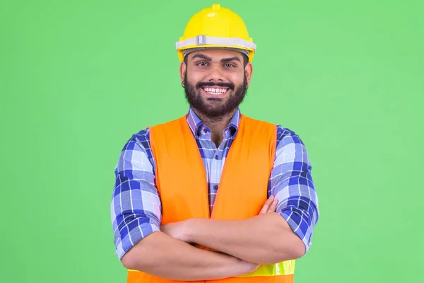 Feliz jovem sobrepeso barbudo indiano trabalhador da construção civil sorrindo com os braços cruzados — Fotografia de Stock