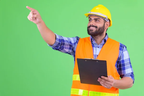 Щасливий молодий надмірна вага Бородаті Індійська людина будівельний працівник тримає буфер обміну і вказівний палець — стокове фото