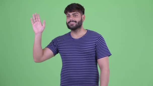 Happy young overweight bearded Indian man waving hand — Stock Video