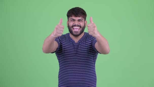 Lycklig ung övervikt skäggiga Indian man ger tummen upp och ser upphetsad — Stockvideo