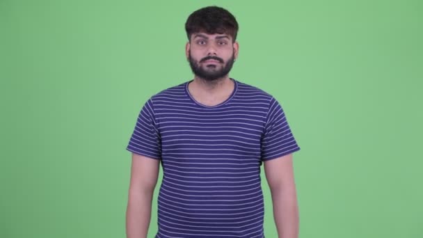 Плутати молоді надмірна вага бородатий індійський чоловік вибираючи між великими пальцями вгору і великі пальці вниз — стокове відео