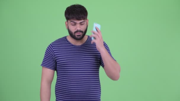 Young overweight bearded Indian man talking on the phone and showing stop gesture — Stock Video