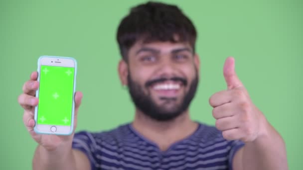 Mutlu genç kilolu sakallı Hintli adamın yüzü telefon gösteren ve başparmak veren — Stok video