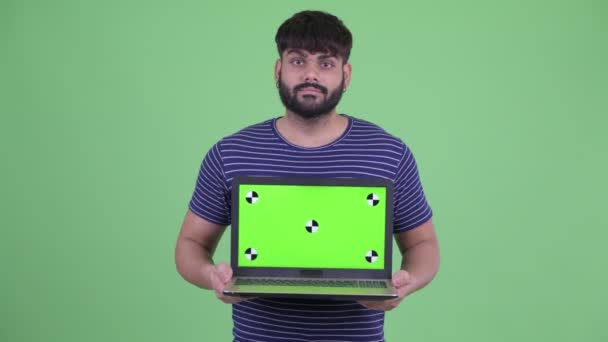 Gelukkig jong overgewicht bebaarde Indiase man toont laptop — Stockvideo