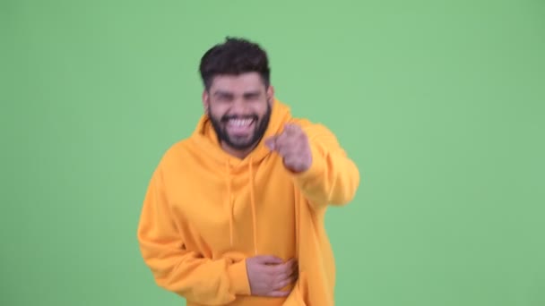 Happy young overweight bearded Indian man laughing and pointing at camera — Stock Video