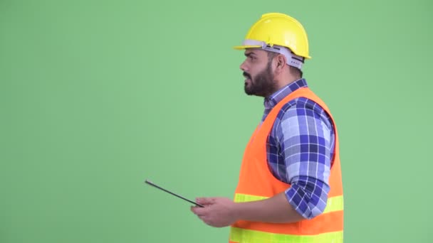 Profilvy över överviktiga skäggiga Indian man byggarbetare pratar medan du håller Urklipp — Stockvideo