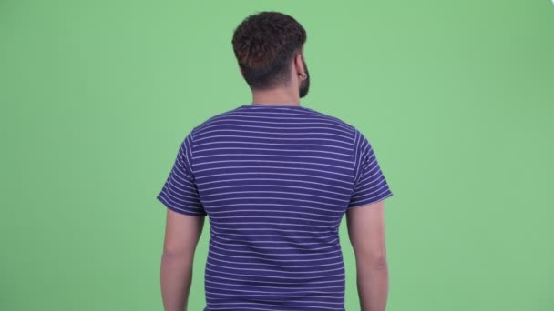 Vista posteriore di giovane barbuto sovrappeso uomo indiano pensare e guardarsi intorno — Video Stock