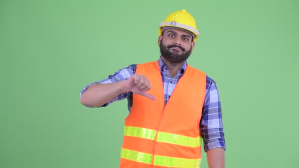 Stressed young overweight bearded Indian man construction worker giving thumbs down — Stock Video