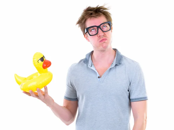 Funny young nerd man with eyeglasses holding inflatable duck and looking bored Stock Image