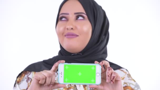 Volto di felice giovane donna africana musulmana pensando mentre mostra il telefono — Video Stock