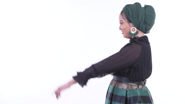 Vue du profil de jeune femme musulmane africaine heureuse pointant du doigt — Video