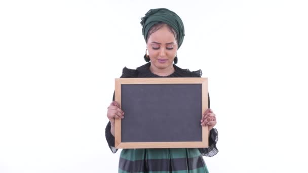 Stressed young African Muslim woman holding blackboard and getting bad news — Stock Video