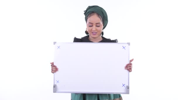 Счастливая молодая африканская мусульманка держит белую доску и получает хорошие новости — стоковое видео