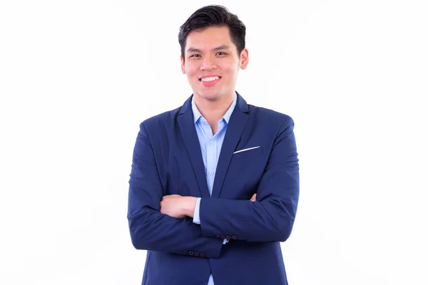 Happy young handsome Asian businessman smiling with arms crossed — Stock Photo, Image