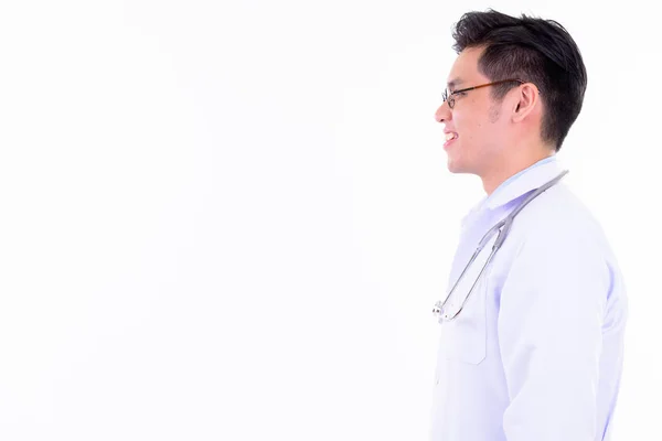 Vue du profil de heureux jeune Asiatique homme médecin souriant — Photo