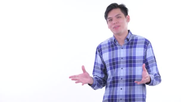 Счастливый молодой азиатский хипстер трогает что-то и говорит — стоковое видео