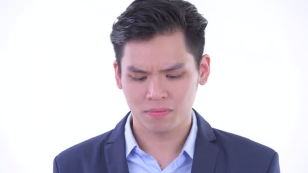 Stresli genç Asyalı işadamının yüzü düşünme ve aşağı bakma — Stok video