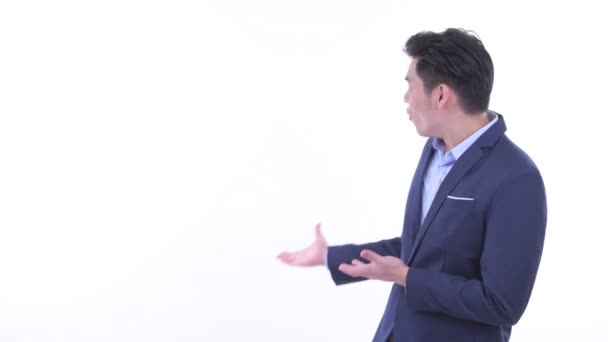 Щасливий молодий Азіатський бізнесмен показуючи на спину і дивлячись схвильований — стокове відео
