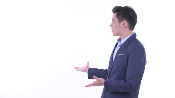 Счастливый молодой азиатский бизнесмен разговаривает, показывая спине — стоковое видео