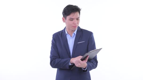 Счастливый молодой азиатский бизнесмен разговаривает, держа планшет — стоковое видео