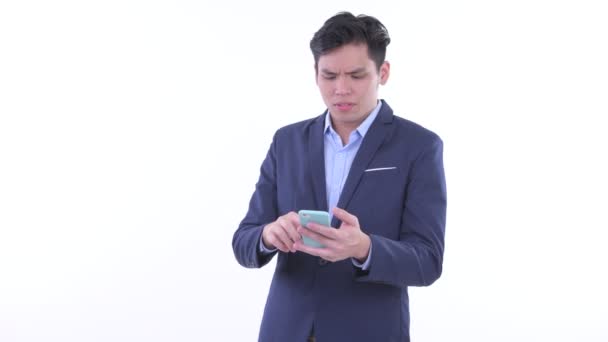 Estresado joven asiático hombre de negocios utilizando el teléfono y recibiendo malas noticias — Vídeos de Stock