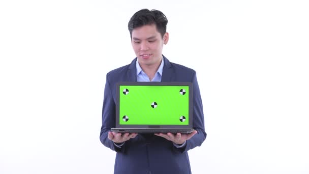 Happy young Asian businessman thinking while showing laptop — Stock Video