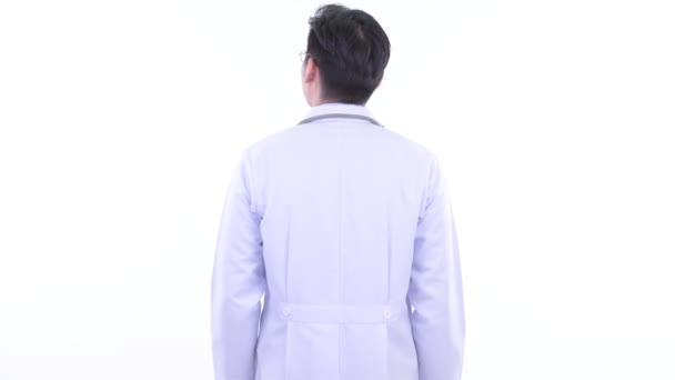 Rear view of young Asian man doctor looking around and examining — Stock Video