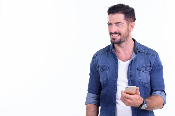 Gelukkig jong bebaarde hipster man denken terwijl het gebruik van telefoon — Stockfoto