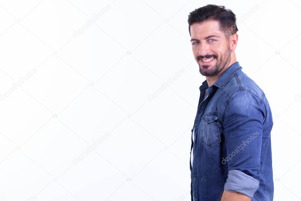 Profile view of happy young bearded hipster man looking at camera