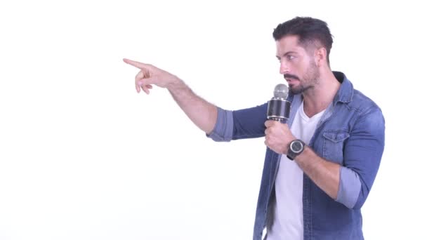 Happy young bearded hipster man as host presenting with microphone — Stock Video