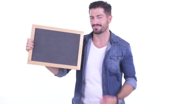 Happy young bearded hipster man holding blackboard and giving thumbs up — Stok Video