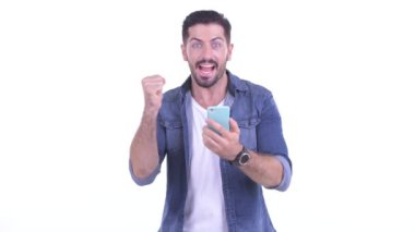 Mutlu genç sakallı hippi telefonu kullanıyor ve iyi haberler alıyor.
