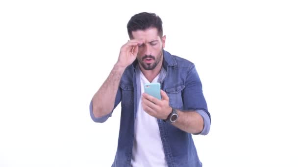Напряженный молодой бородатый хипстер пользуется телефоном и получает плохие новости — стоковое видео