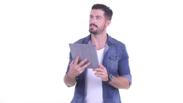 Feliz jovem barbudo hipster homem pensando ao usar tablet digital — Vídeo de Stock