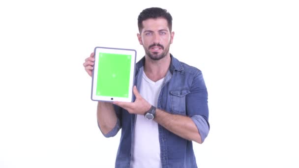 Happy young bearded hipster man talking while showing digital tablet — Stock Video