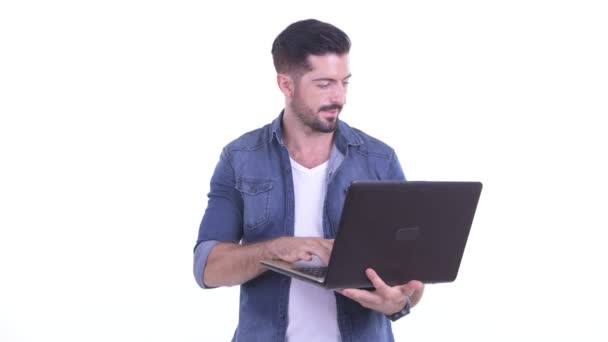 Happy Young bebaarde hipster man praten tijdens het gebruik van laptop — Stockvideo