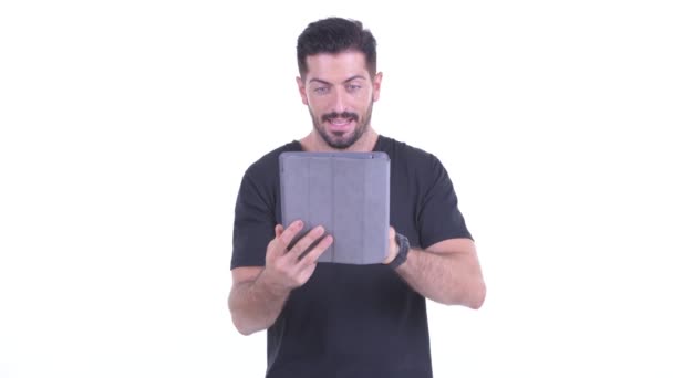 Feliz joven guapo barbudo hombre usando tableta digital y recibiendo buenas noticias — Vídeo de stock