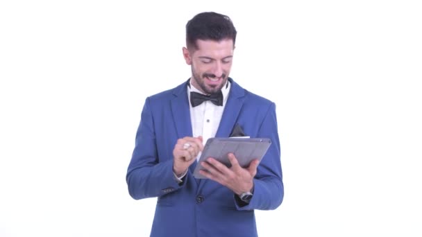 Happy young bearded businessman talking while using digital tablet — Stock Video