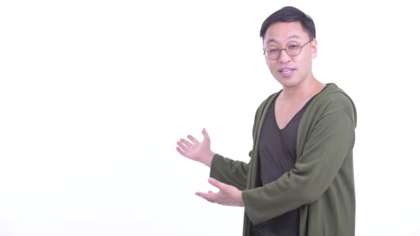Felice uomo giapponese con occhiali da vista parlando mentre mostra alla schiena — Video Stock