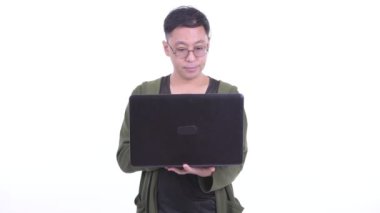 Happy Japanese man with eyeglasses thinking while using laptop