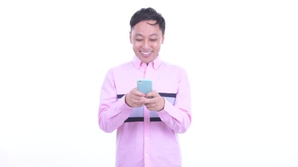 Feliz empresario japonés pensando mientras usa el teléfono — Vídeo de stock