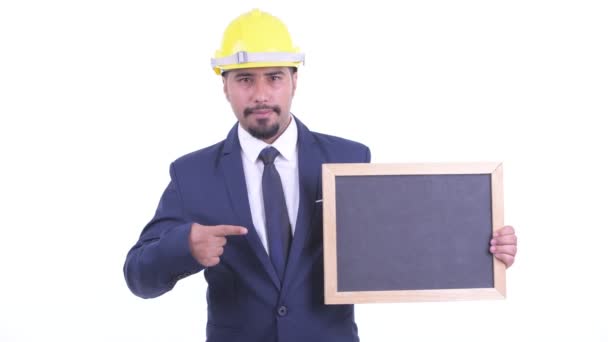 Feliz hombre de negocios persa barbudo como ingeniero sosteniendo pizarra y dando pulgares hacia arriba — Vídeos de Stock