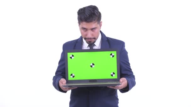 Happy bearded Persian businessman thinking while showing laptop — Stock Video