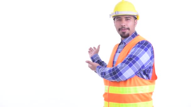Happy bearded Persian man construction worker talking while showing to the back — Stock Video