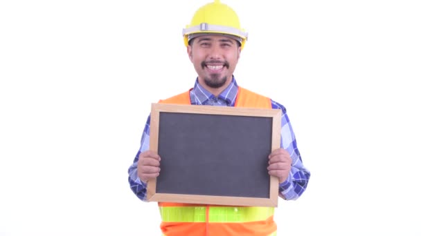 Happy bearded Persian man construction worker talking while holding blackboard — Stock Video